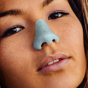 Angled face of a young women with blue Nöz sunblock applied to the nose