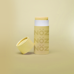 Yellow Nöz product with the cap angled on the bottle's side in front of yellow backround